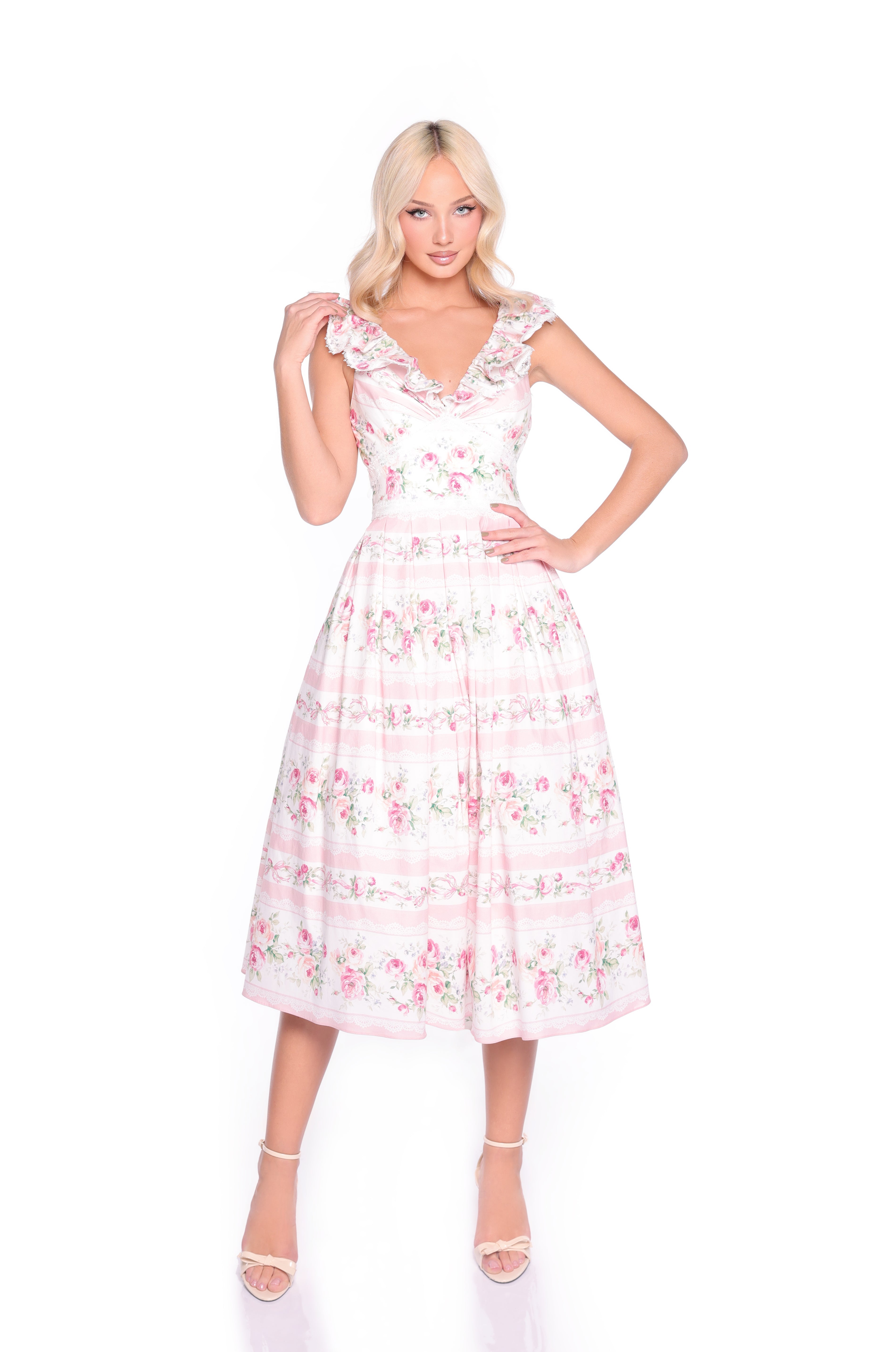 A woman models the Pink Floral Casual Midi Dress: Rosette—a light pink floral midi dress with a ruffled neckline and sleeveless design—styled with white strappy heels against a white background.